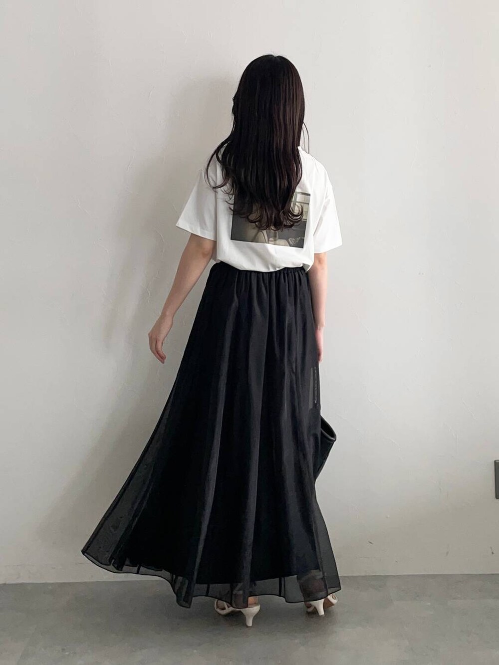 ブラック系のハンドバッグ、ホワイト系のサンダル、ブラック系のスカートを着用したレディースの春コーディネートの2枚目の写真