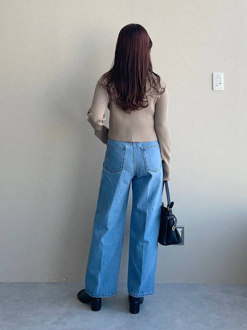 ブラック系のショルダーバッグ、ブルー系のデニムパンツ、ブラック系のパンプスを着用したレディースの冬コーディネートの2枚目の写真