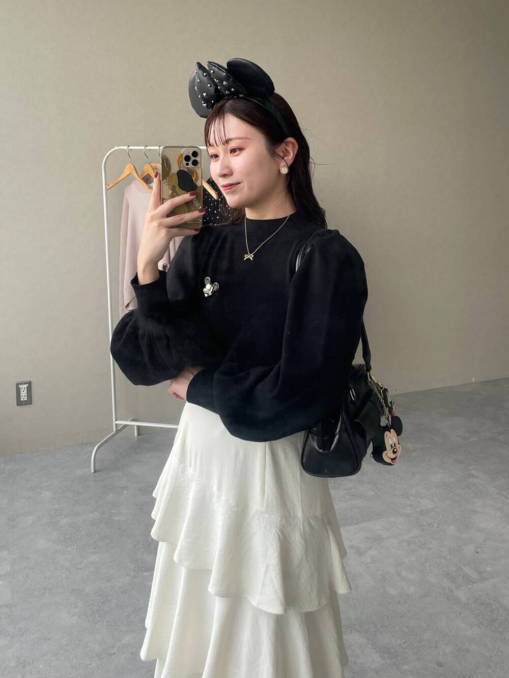 ホワイト系のブーツ、ホワイト系のスカート、ブラック系のハンドバッグを着用したレディースの秋コーディネートの5枚目の写真