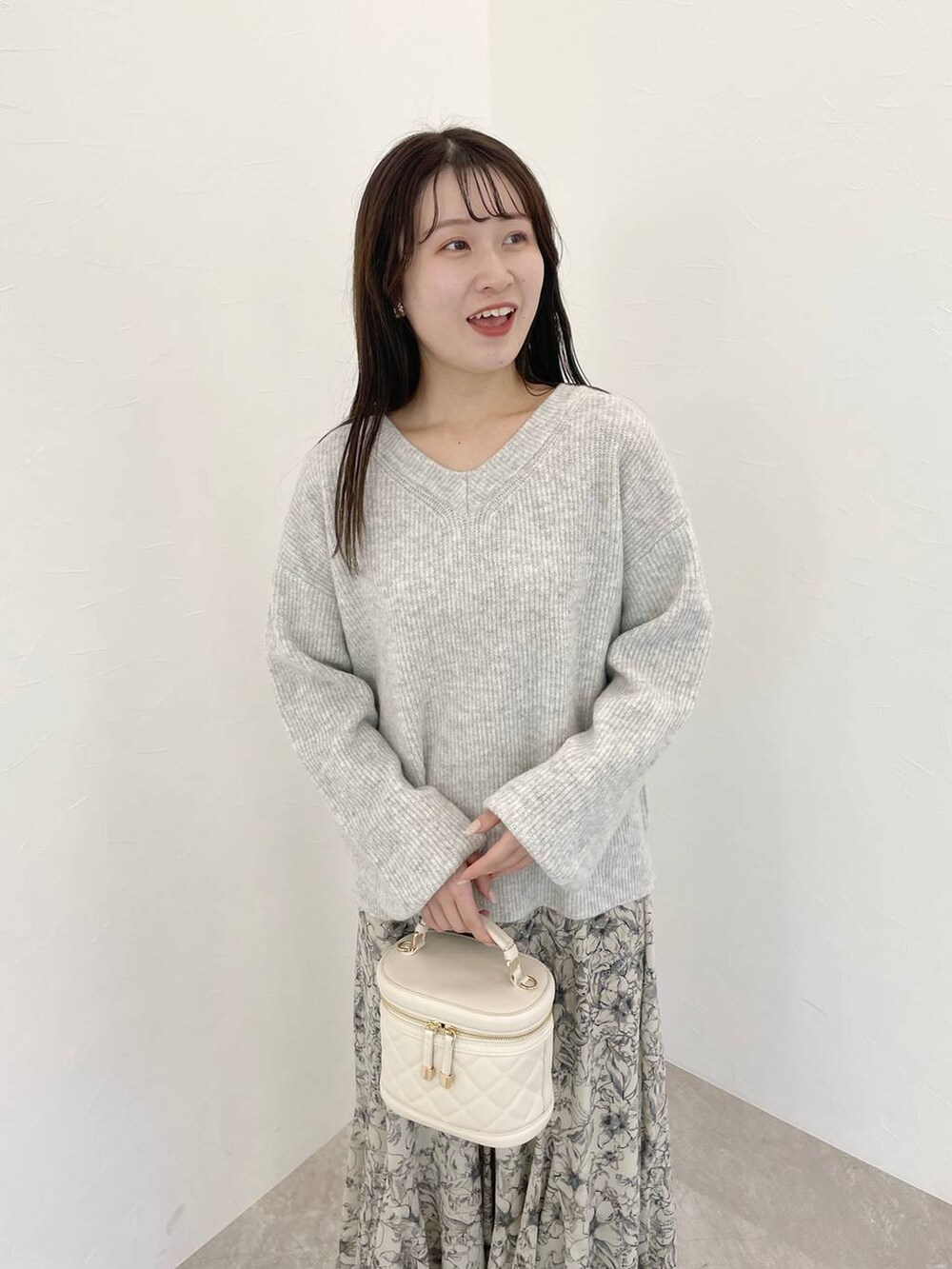 グレー系のニット/セーター、ベージュ系のスカート、ホワイト系のショルダーバッグを着用したレディースの冬コーディネートの3枚目の写真