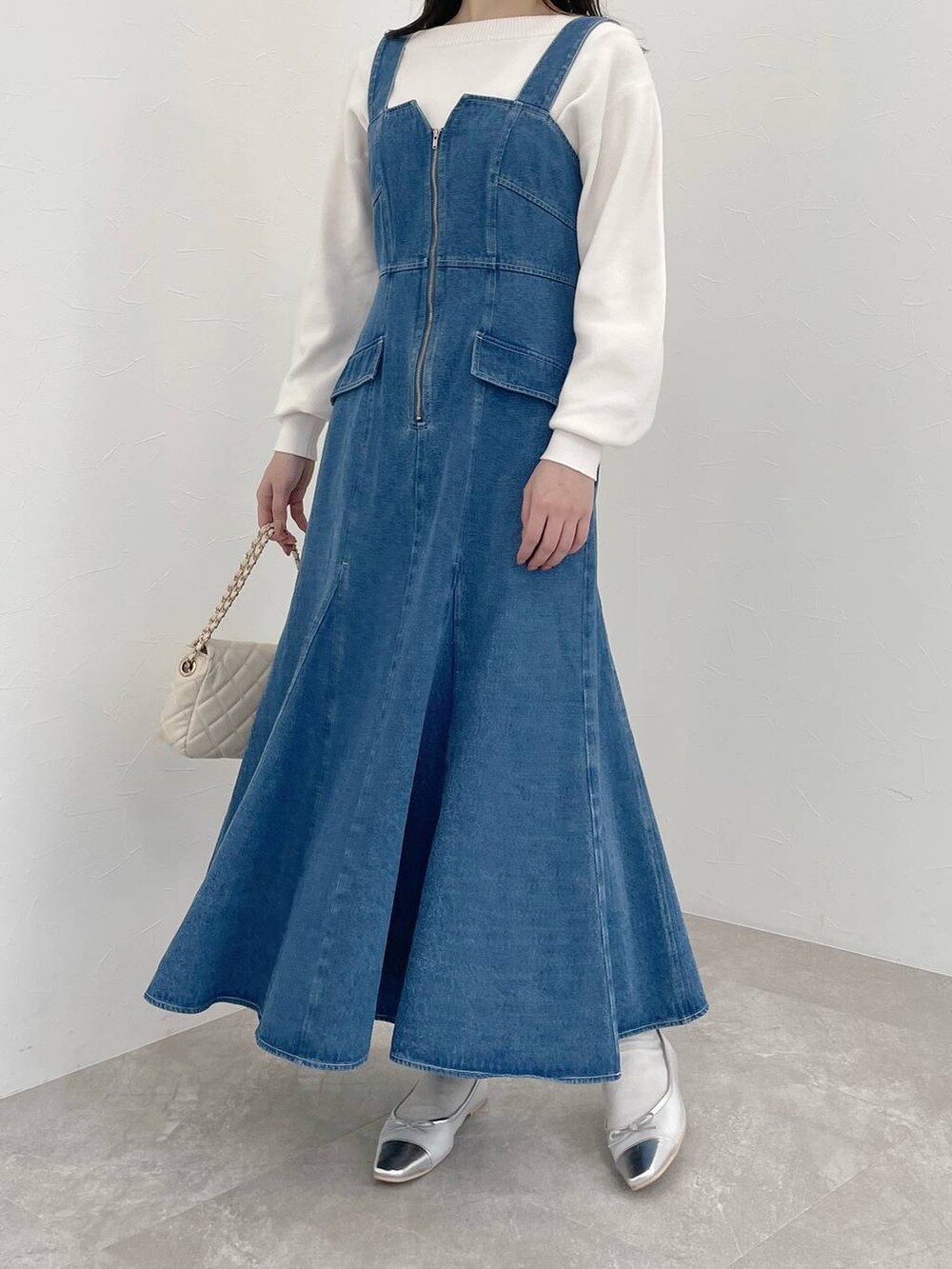 シルバー系のバレエシューズ、ホワイト系のショルダーバッグ、ブルー系のジャンパースカートを着用したレディースの春コーディネートの4枚目の写真