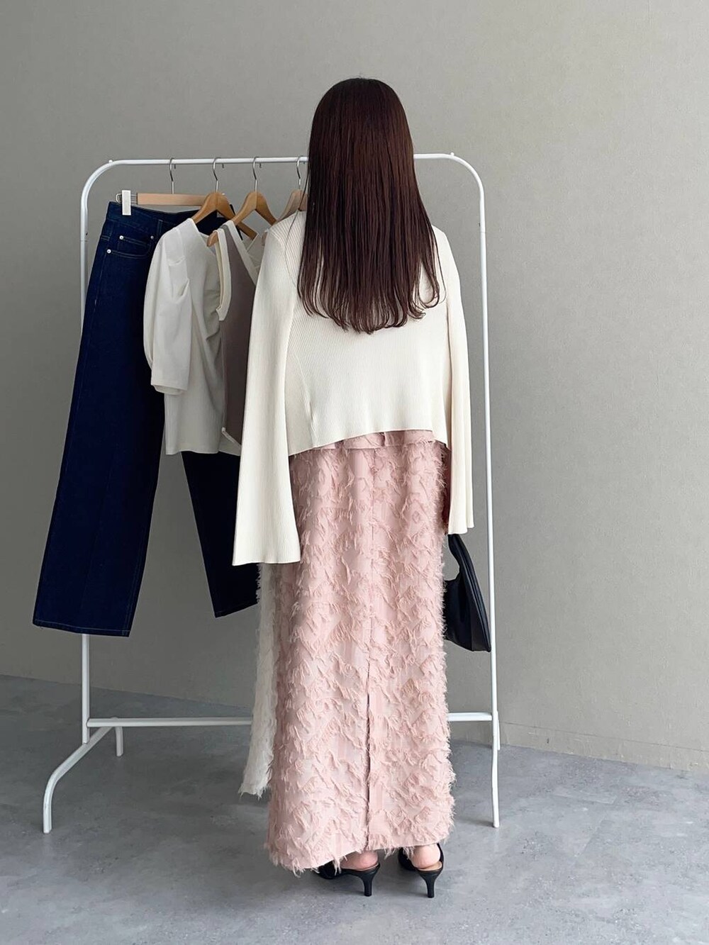 ブラック系のパンプス、ブラック系のハンドバッグ、ピンク系のワンピースを着用したレディースの夏コーディネートの2枚目の写真