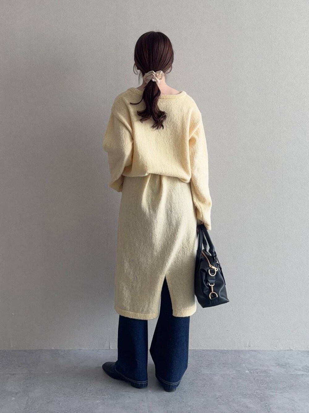 ブラック系のボストンバッグ、ブラック系のローファー、イエロー系のワンピースを着用したレディースの冬コーディネートの2枚目の写真