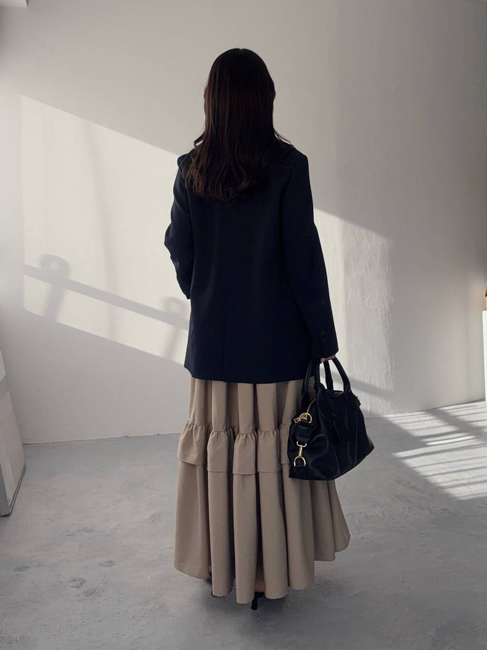 ブラック系のボストンバッグ、ブルー系のテーラードジャケット、ブラック系のサンダルを着用したレディースの冬コーディネートの2枚目の写真