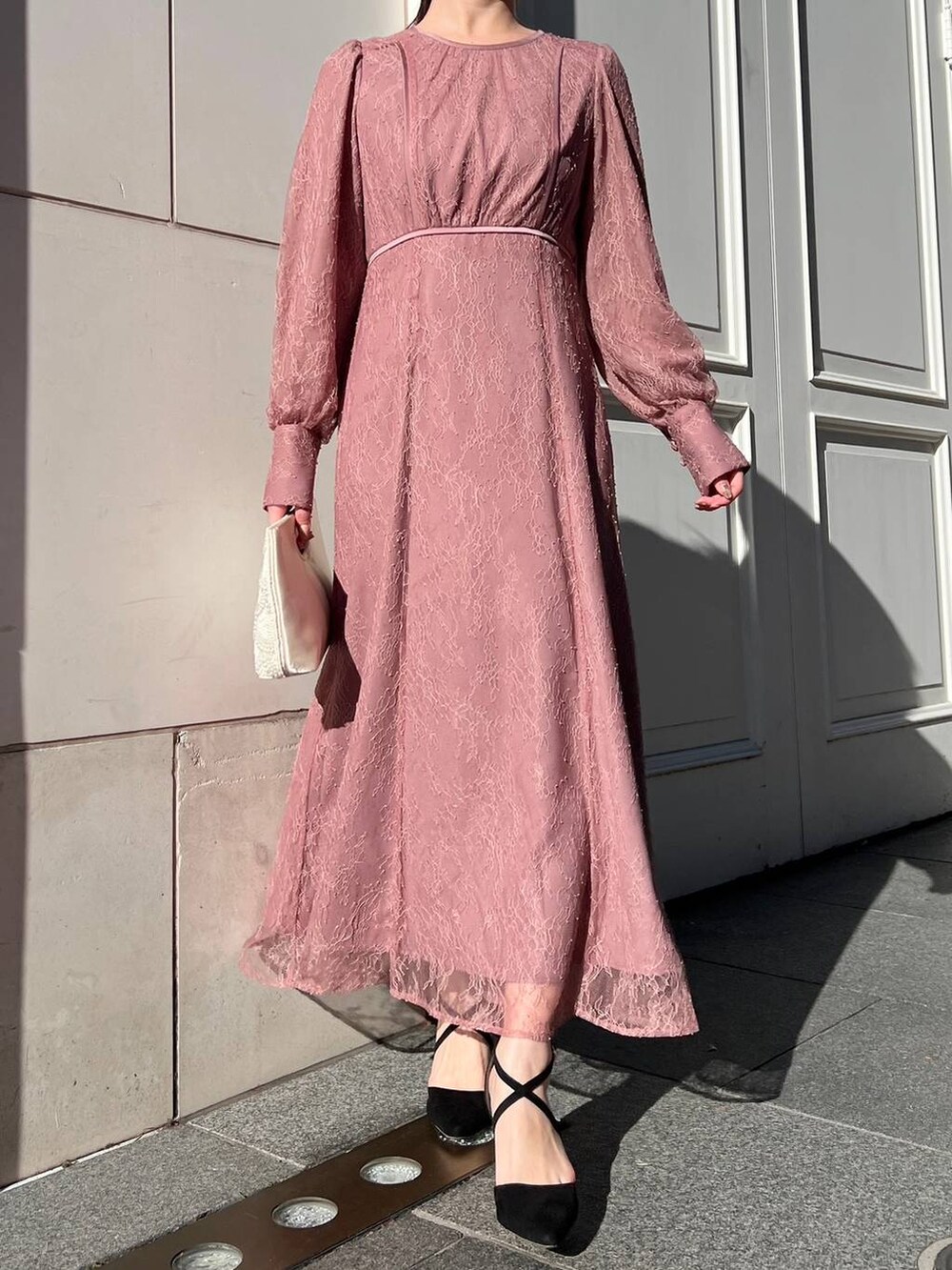 ピンク系のドレス、ベージュ系のクラッチバッグを着用したレディースの冬コーディネートの2枚目の写真