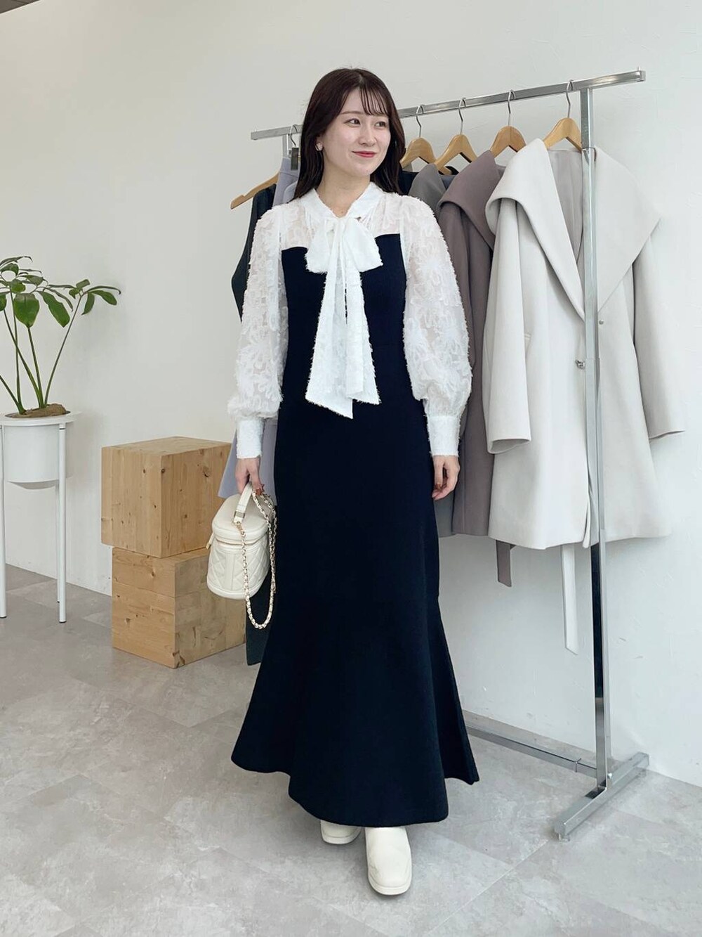 ブラック系のその他アウター、ホワイト系のブーツ、ホワイト系のショルダーバッグを着用したレディースの秋コーディネートの3枚目の写真