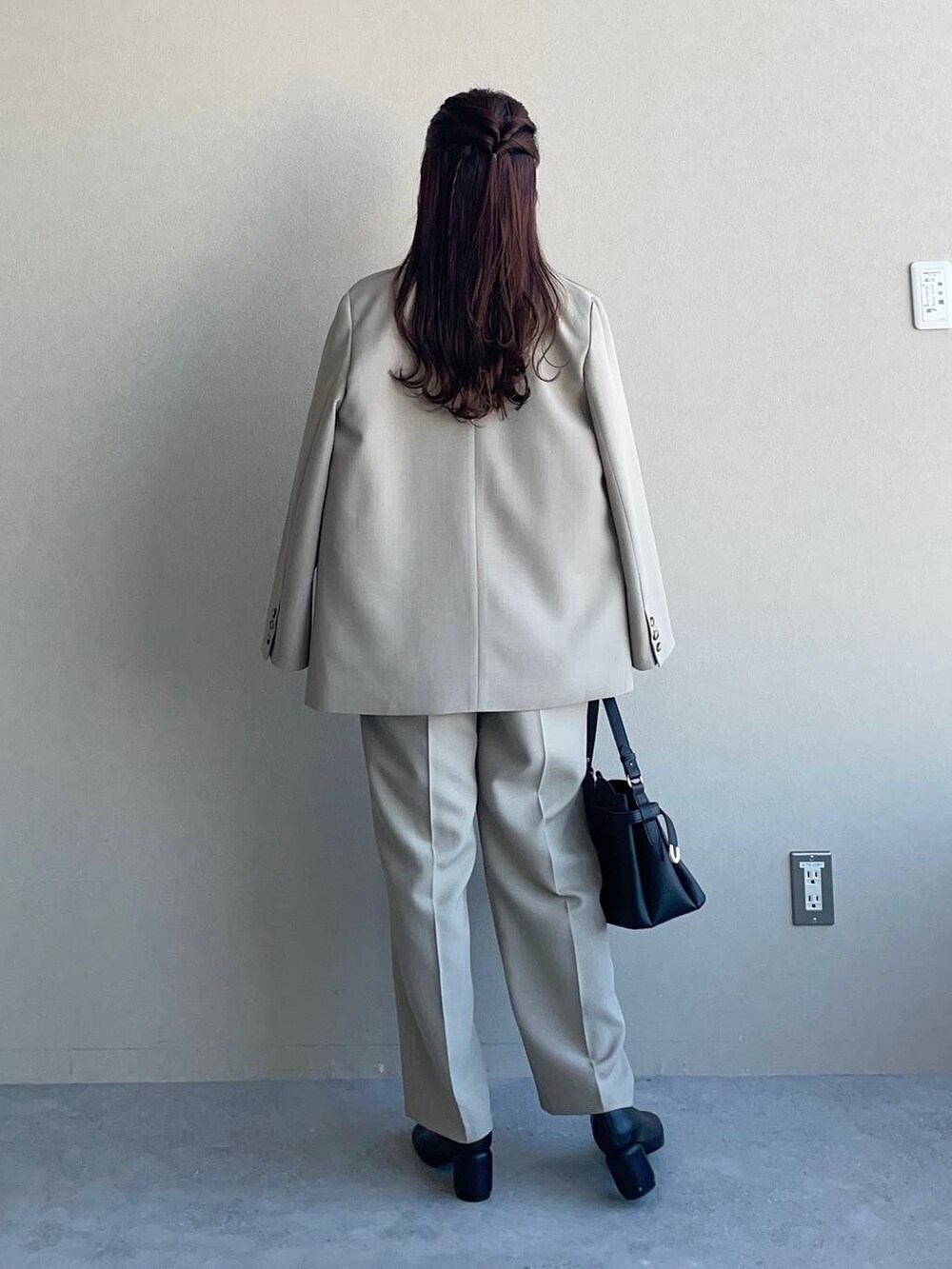 ブラック系のショルダーバッグ、ベージュ系のテーラードジャケット、ベージュ系のスラックスを着用したレディースの冬コーディネートの2枚目の写真