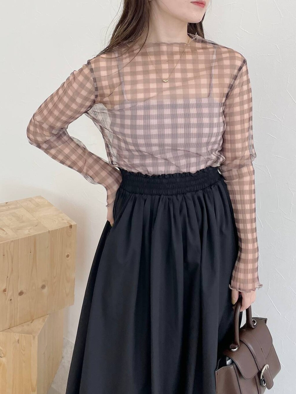 ブラック系のスカート、ブラウン系のハンドバッグ、ブラック系のパンプスを着用したレディースの秋コーディネートの3枚目の写真