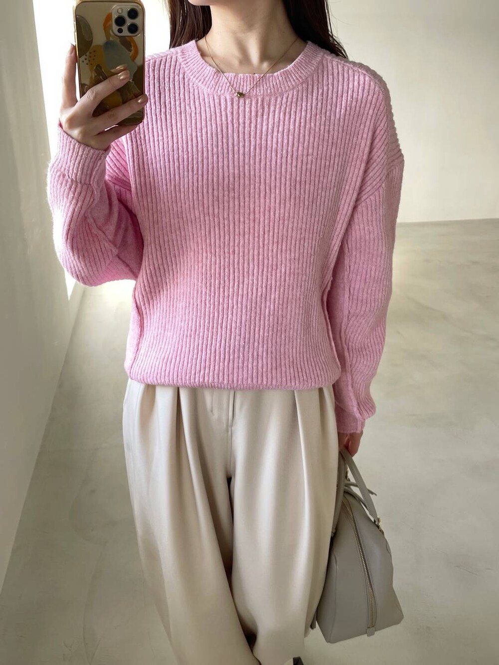 ベージュ系のハンドバッグ、ブラウン系のブーツ、ピンク系のニット/セーターを着用したレディースの冬コーディネートの3枚目の写真