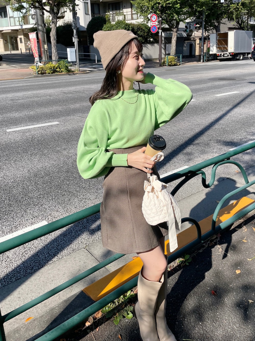 グリーン系のニット/セーター、ブラウン系のスカート、ベージュ系のブーツを着用したレディースの秋コーディネートの3枚目の写真