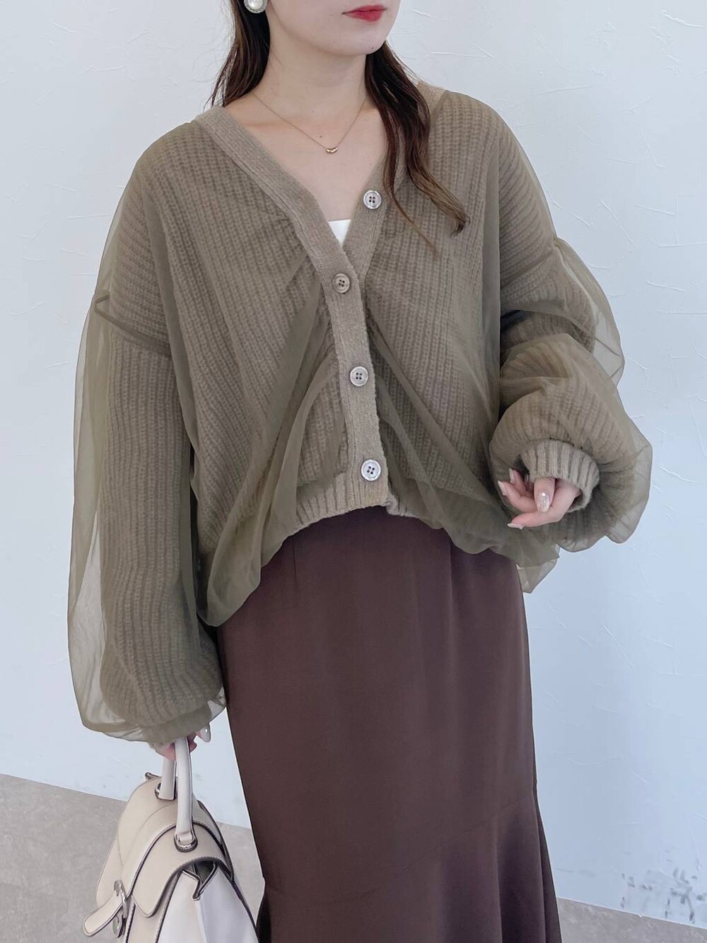 ホワイト系のハンドバッグ、ホワイト系のブーツ、ブラウン系のスカートを着用したレディースの秋コーディネートの3枚目の写真