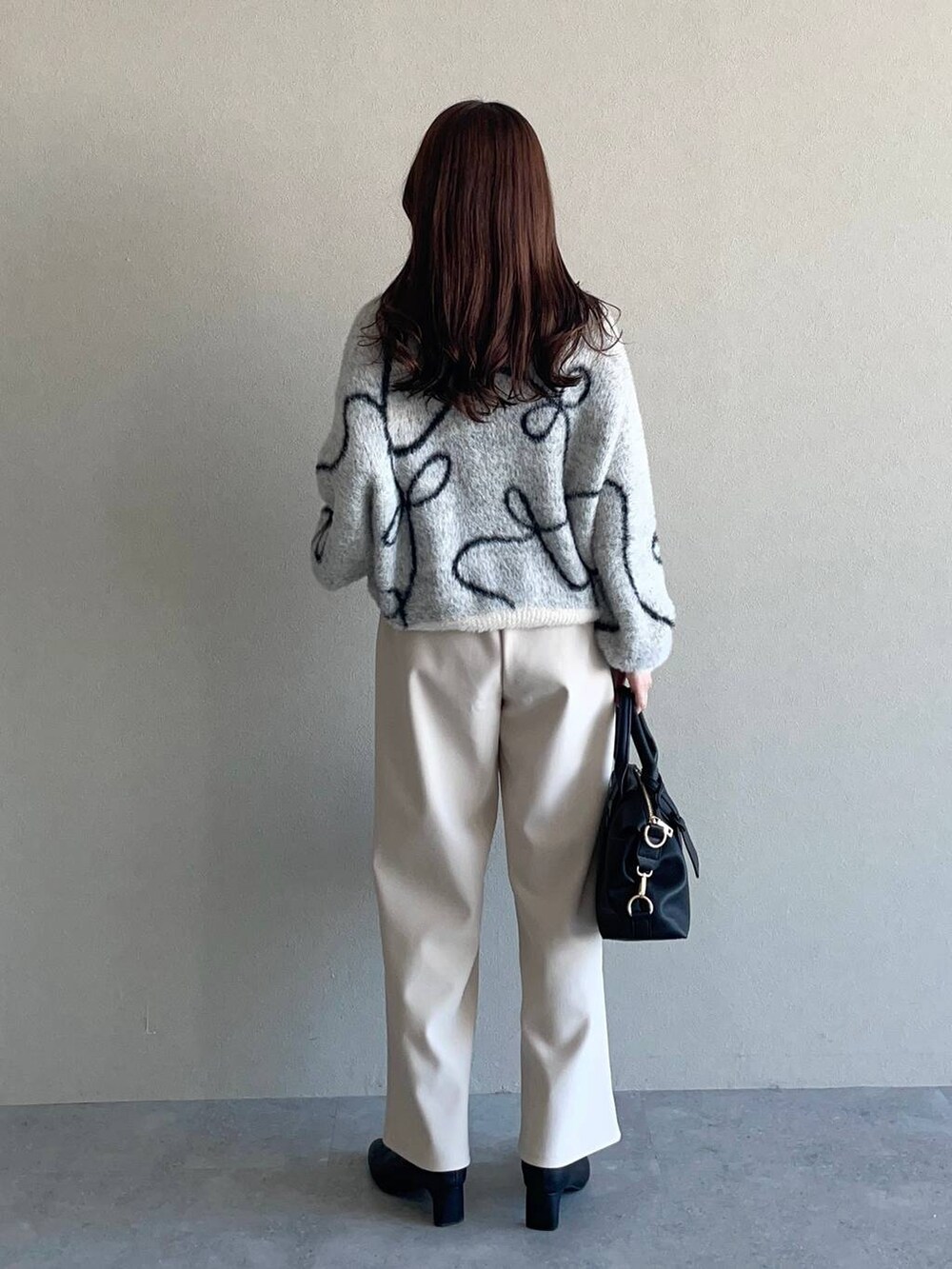 グレー系のピーコート、ブラック系のボストンバッグ、ブラック系のブーツを着用したレディースの冬コーディネートの4枚目の写真