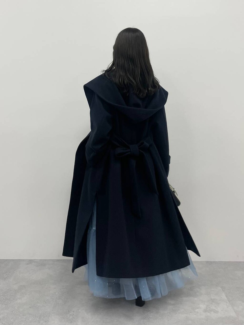 ブルー系のノーカラーコート、ブラック系のハンドバッグ、ブラック系のブーツを着用したレディースの秋コーディネートの3枚目の写真