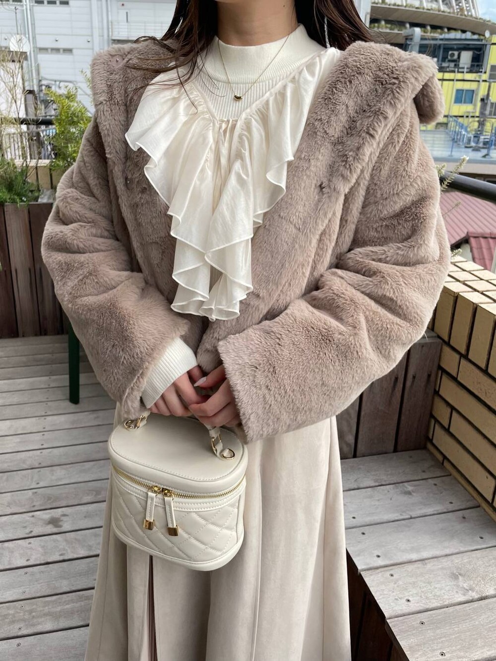 ホワイト系のショルダーバッグ、ブラウン系のブーツ、ベージュ系のブルゾンを着用したレディースの冬コーディネートの3枚目の写真