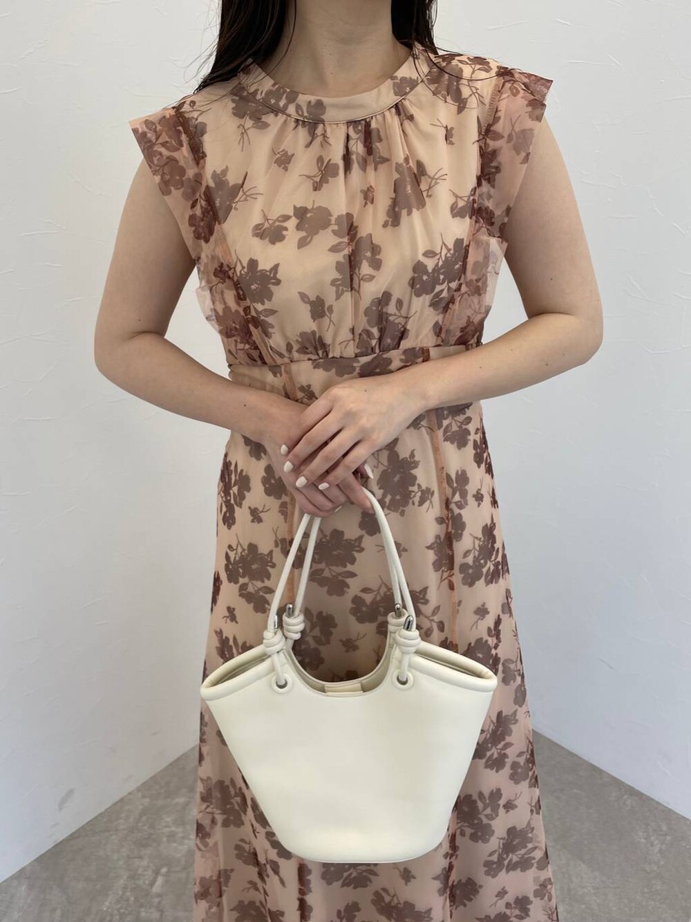ホワイト系のハンドバッグ、ホワイト系のサンダル、ベージュ系のワンピースを着用したレディースの春コーディネートの3枚目の写真