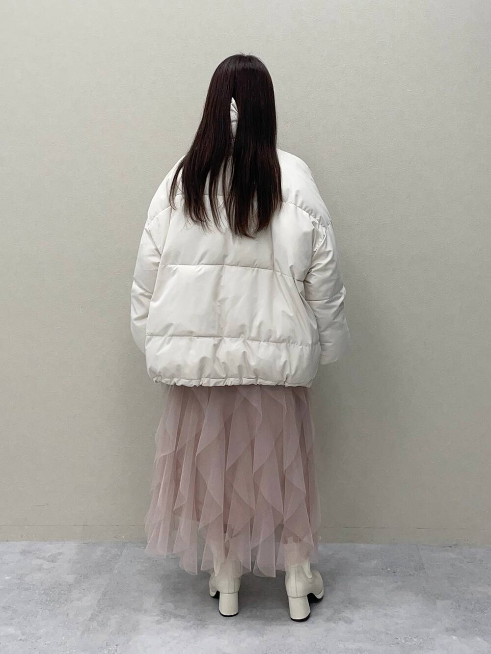 ホワイト系のブーツ、ホワイト系のブルゾン、ピンク系のスカートを着用したレディースの冬コーディネートの2枚目の写真