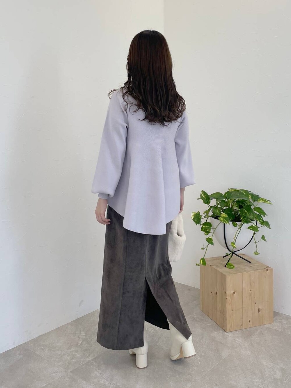 ブラウン系のスカート、ホワイト系のブーツ、ホワイト系のハンドバッグを着用したレディースの冬コーディネートの2枚目の写真