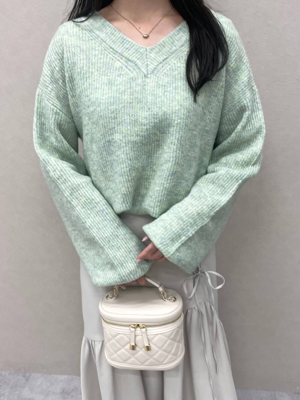グリーン系のニット/セーター、ホワイト系のブーツ、ホワイト系のショルダーバッグを着用したレディースの冬コーディネートの4枚目の写真