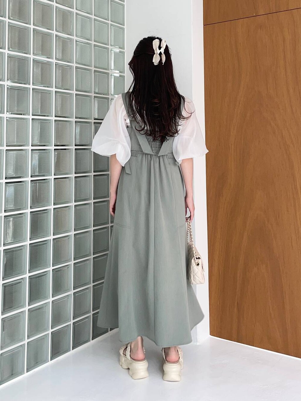 グリーン系のジャンパースカート、ホワイト系のショルダーバッグ、ホワイト系のサンダルを着用したレディースの夏コーディネートの2枚目の写真