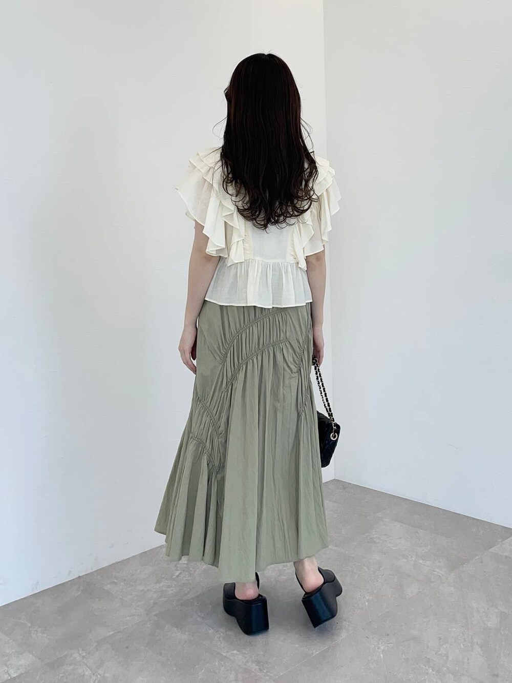 ブラック系のサンダル、ホワイト系のシャツ/ブラウス、ブラック系のショルダーバッグを着用したレディースの春コーディネートの2枚目の写真