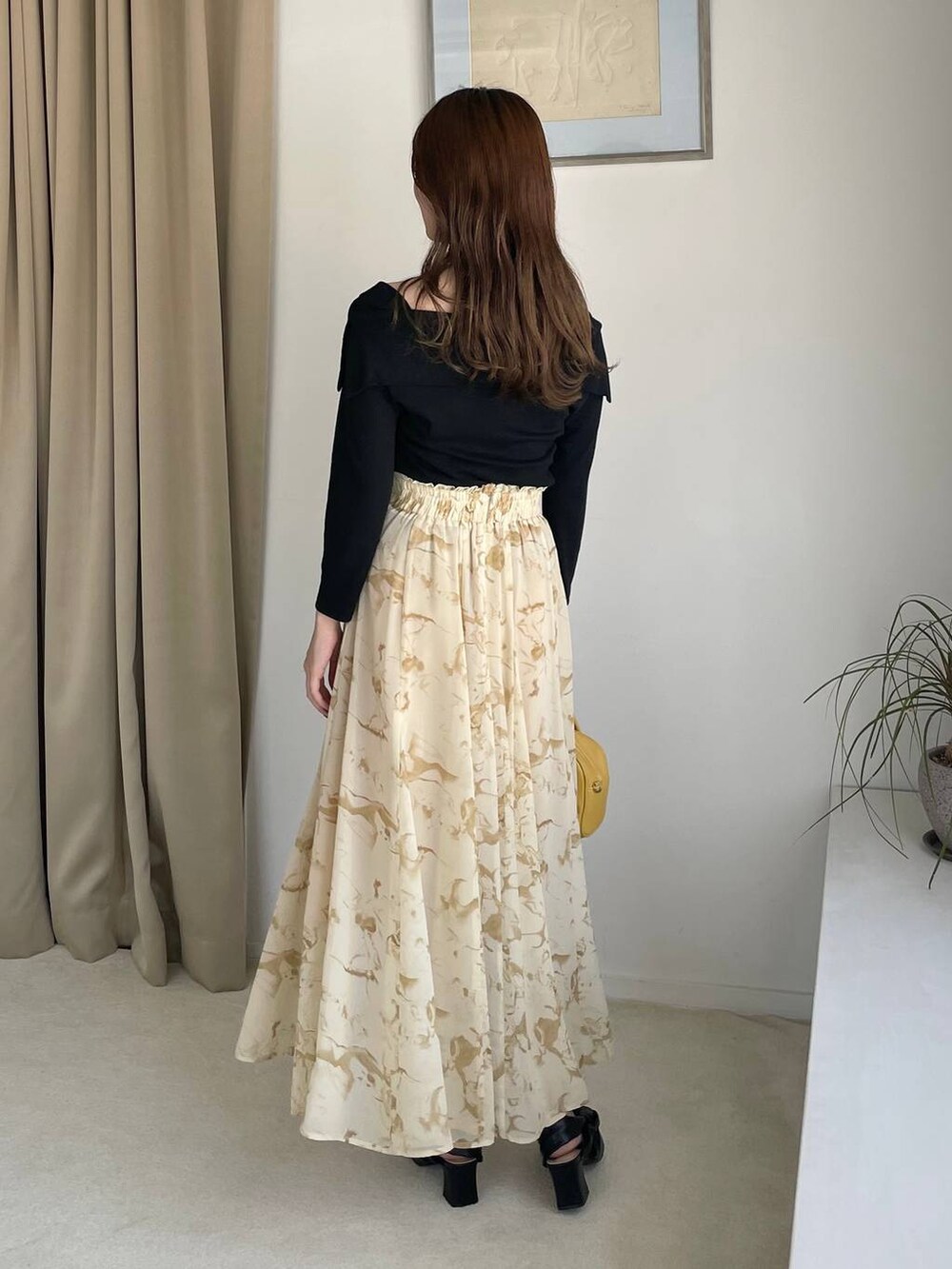 イエロー系のスカート、イエロー系のボストンバッグ、ブラック系のTシャツ/カットソーを着用したレディースの夏コーディネートの2枚目の写真