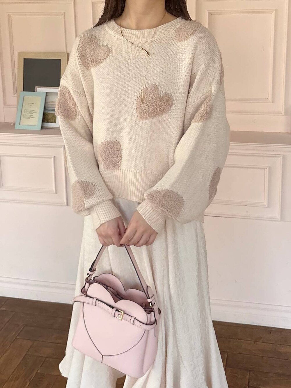 ピンク系のショルダーバッグ、ホワイト系のブーツ、ホワイト系のスカートを着用したレディースの冬コーディネートの3枚目の写真