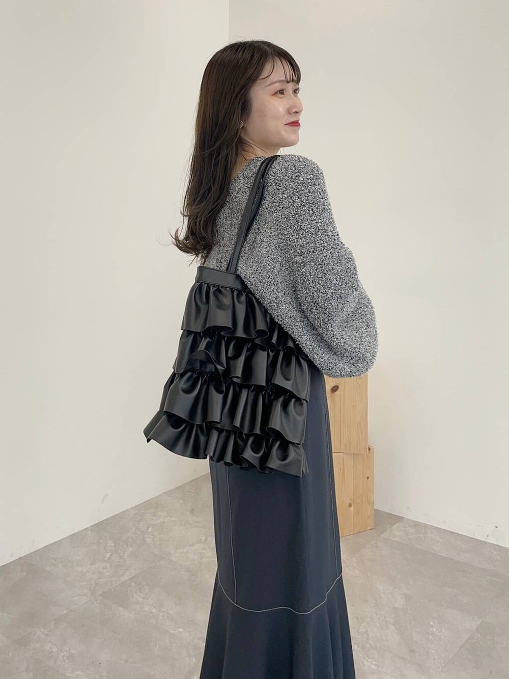 ブラック系のブーツ、グレー系のスカート、ブラック系のトートバッグを着用したレディースの秋コーディネートの4枚目の写真