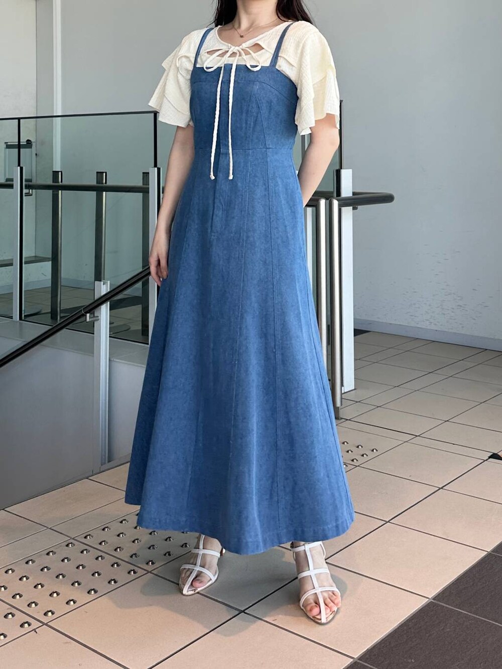 ブルー系のジャンパースカート、ホワイト系のサンダル、ホワイト系のTシャツ/カットソーを着用したレディースの夏コーディネートの4枚目の写真