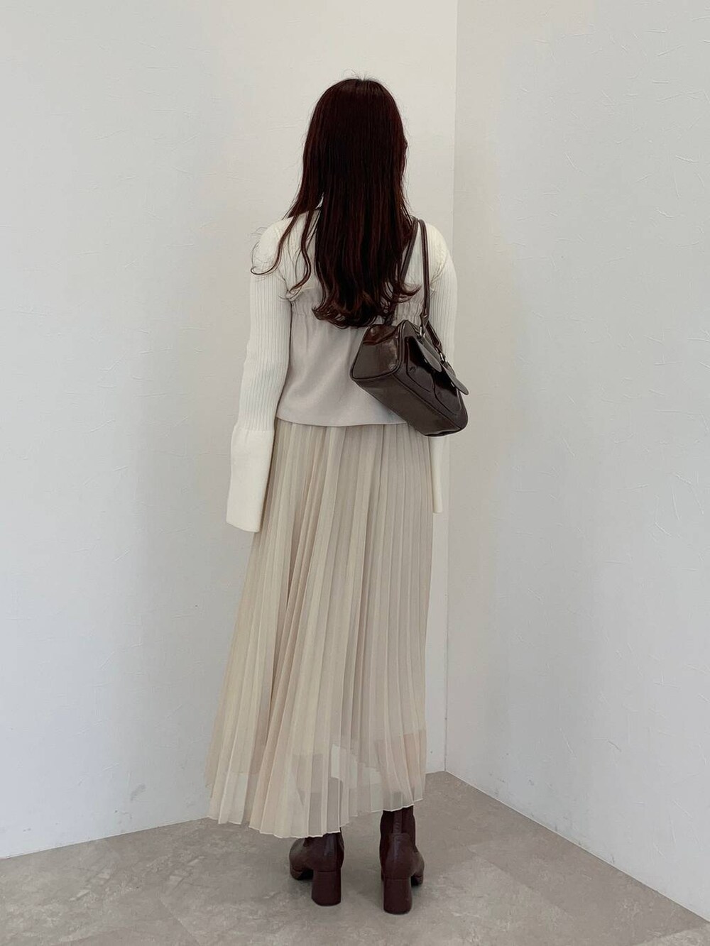 ブラウン系のブーツ、ホワイト系のニット/セーター、ブラウン系のハンドバッグを着用したレディースの冬コーディネートの2枚目の写真