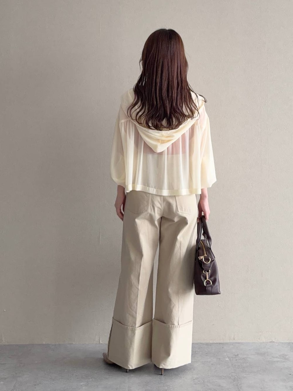 ホワイト系のパーカー、ブラウン系のボストンバッグ、ブラウン系のサンダルを着用したレディースの春コーディネートの2枚目の写真