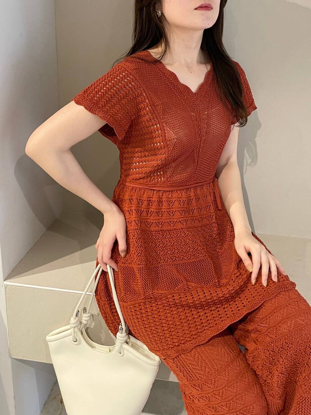 ホワイト系のハンドバッグ、オレンジ系のニット/セーター、ホワイト系のサンダルを着用したレディースの春コーディネートの3枚目の写真