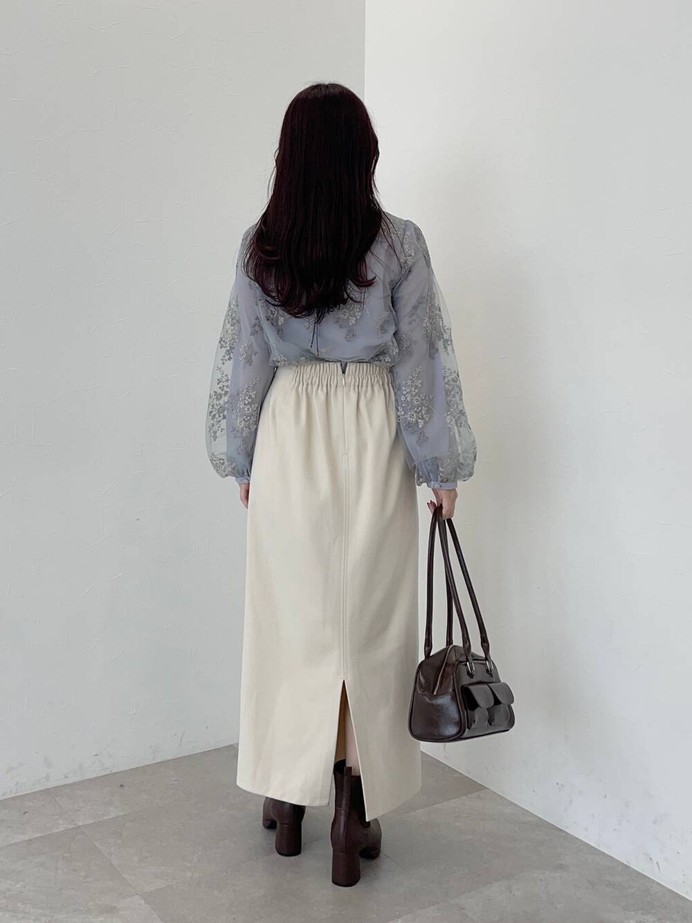 ブルー系のシャツ/ブラウス、ブラウン系のブーツ、ホワイト系のスカートを着用したレディースの冬コーディネートの2枚目の写真