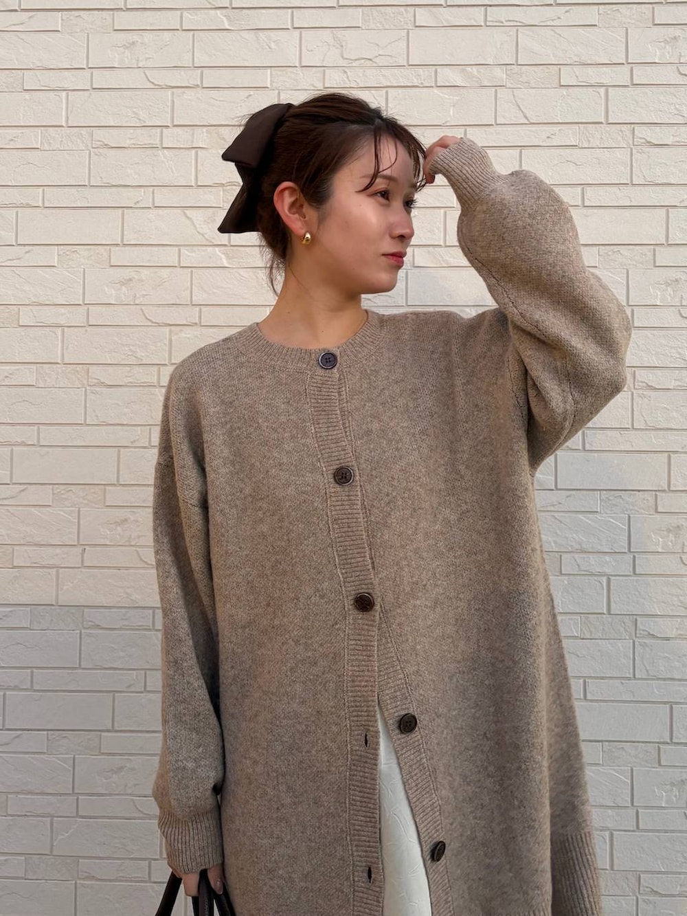 ホワイト系のスカート、ブラウン系のボストンバッグ、ベージュ系のカーディガン/ボレロを着用したレディースの冬コーディネートの4枚目の写真