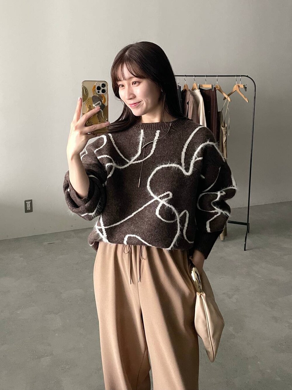 ベージュ系のハンドバッグ、ブラウン系のニット/セーター、ブラウン系のブーツを着用したレディースの秋コーディネートの3枚目の写真