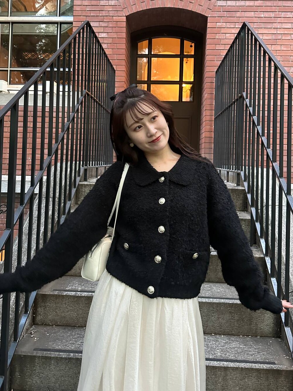 ブラック系のカーディガン/ボレロ、ホワイト系のスカートを着用したレディースの秋コーディネートの6枚目の写真