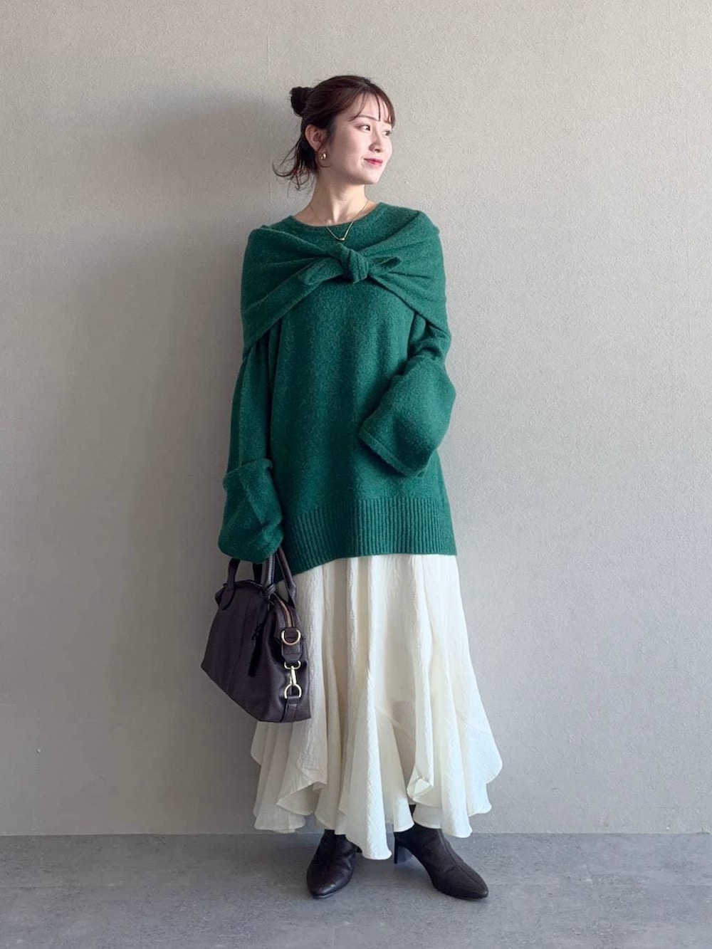 ブラウン系のボストンバッグ、ホワイト系のスカート、ブラウン系のブーツを着用したレディースの冬コーディネートの4枚目の写真