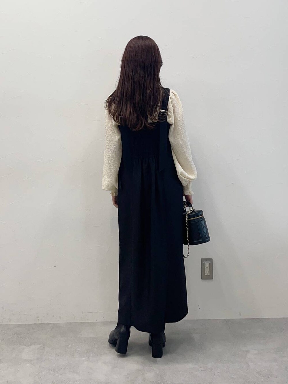 ブラック系のブーツ、ブラック系のジャンパースカート、ブラック系のショルダーバッグを着用したレディースの秋コーディネートの4枚目の写真