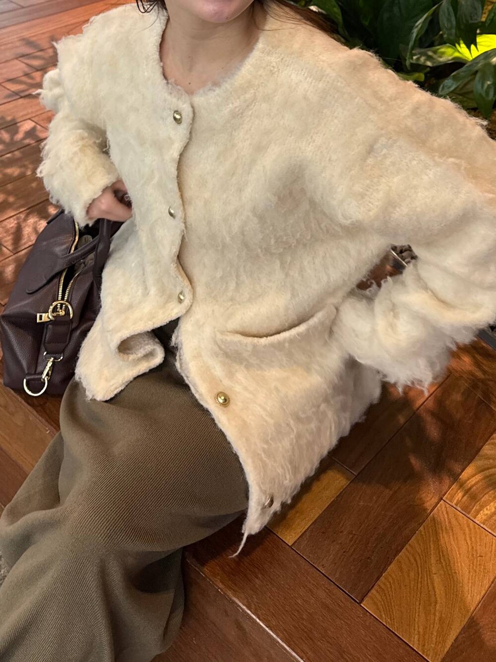 ブラウン系のボストンバッグ、ブラウン系のスカート、ホワイト系のカーディガン/ボレロを着用したレディースの冬コーディネートの4枚目の写真