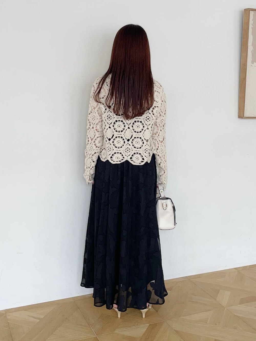 ブラック系のワンピース、ゴールド系のパンプス、ホワイト系のショルダーバッグを着用したレディースの夏コーディネートの2枚目の写真