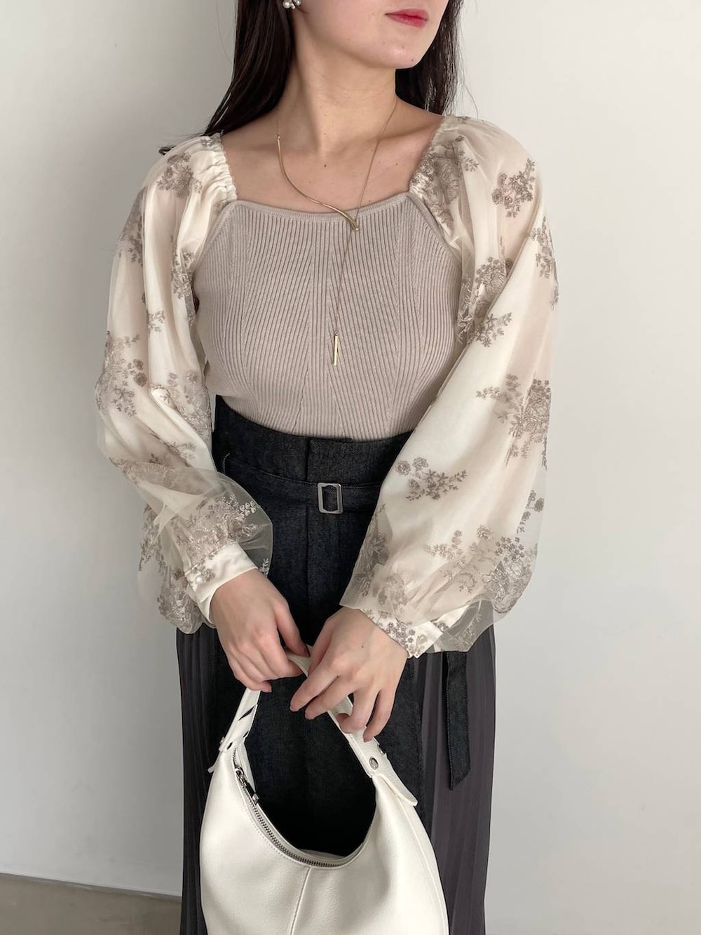 ブラック系のパンプス、ブラック系のスカート、ホワイト系のニット/セーターを着用したレディースの春コーディネートの3枚目の写真