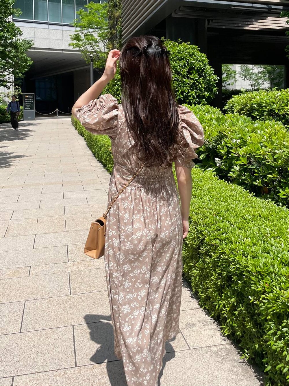 ブラウン系のショルダーバッグ、ベージュ系のワンピースを着用したレディースの春コーディネートの2枚目の写真