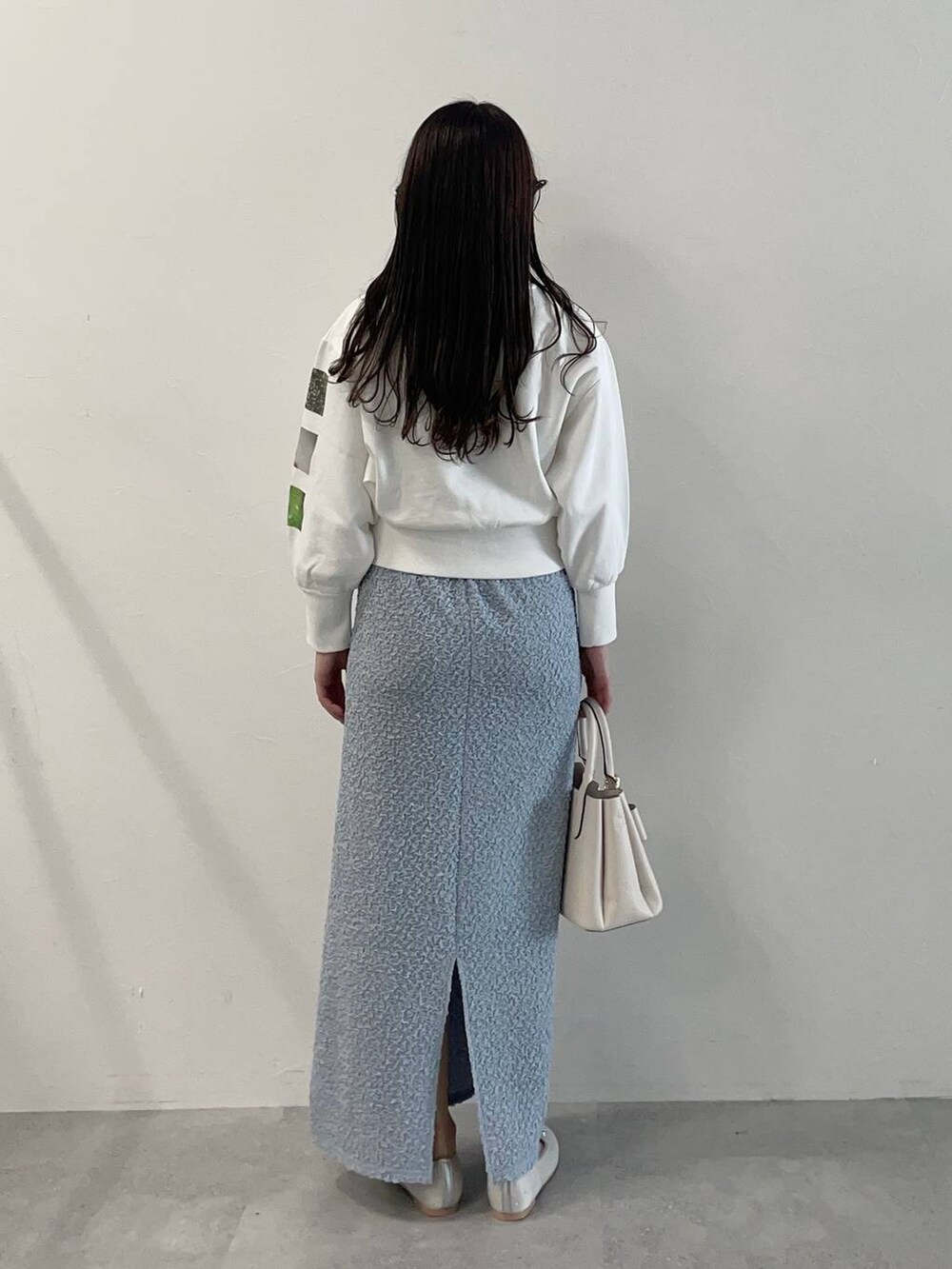 ホワイト系のショルダーバッグ、シルバー系のバレエシューズ、ブルー系のスカートを着用したレディースの春コーディネートの2枚目の写真