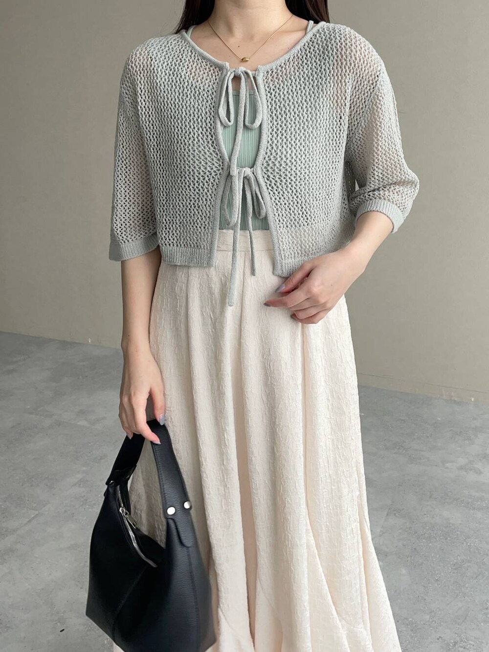 ホワイト系のスカート、グリーン系のカーディガン/ボレロ、ブラック系のショルダーバッグを着用したレディースの春コーディネートの3枚目の写真