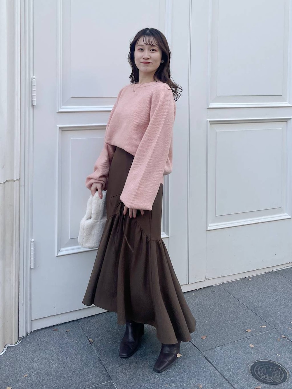 ピンク系のニット/セーター、ホワイト系のその他アウター、ホワイト系のハンドバッグを着用したレディースの秋コーディネートの4枚目の写真