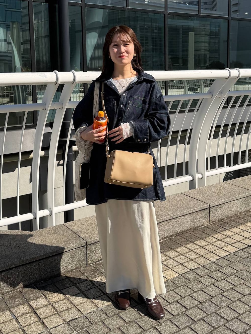 ホワイト系のスカート、ゴールド系のボストンバッグ、ホワイト系のTシャツ/カットソーを着用したレディースの冬コーディネートの3枚目の写真