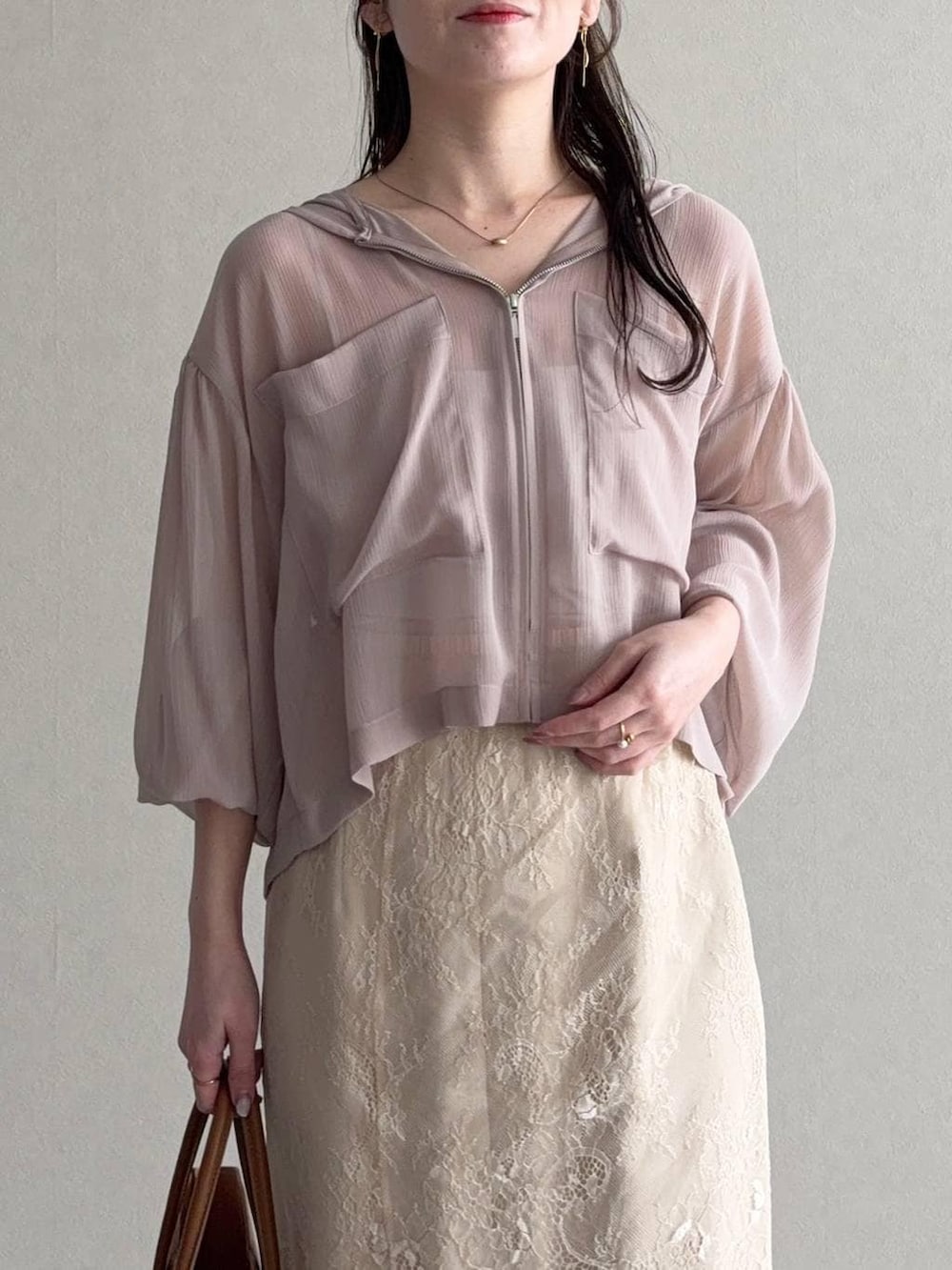 ベージュ系のパーカー、ブラウン系のトートバッグ、ベージュ系のスカートを着用したレディースの春コーディネートの3枚目の写真