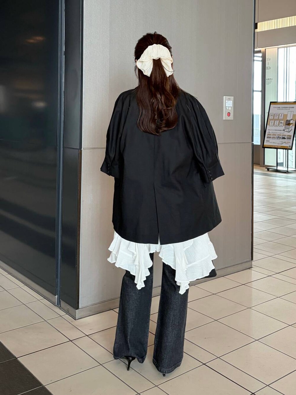 ブラック系のデニムパンツ、ブラック系のサンダル、ホワイト系のチュニックを着用したレディースの春コーディネートの2枚目の写真