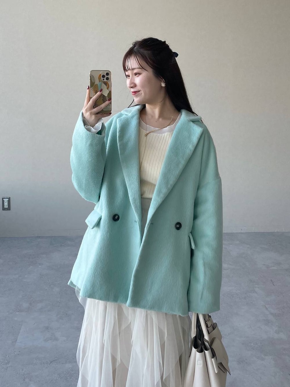 ホワイト系のブーツ、ホワイト系のショルダーバッグ、グリーン系のテーラードジャケットを着用したレディースの冬コーディネートの3枚目の写真