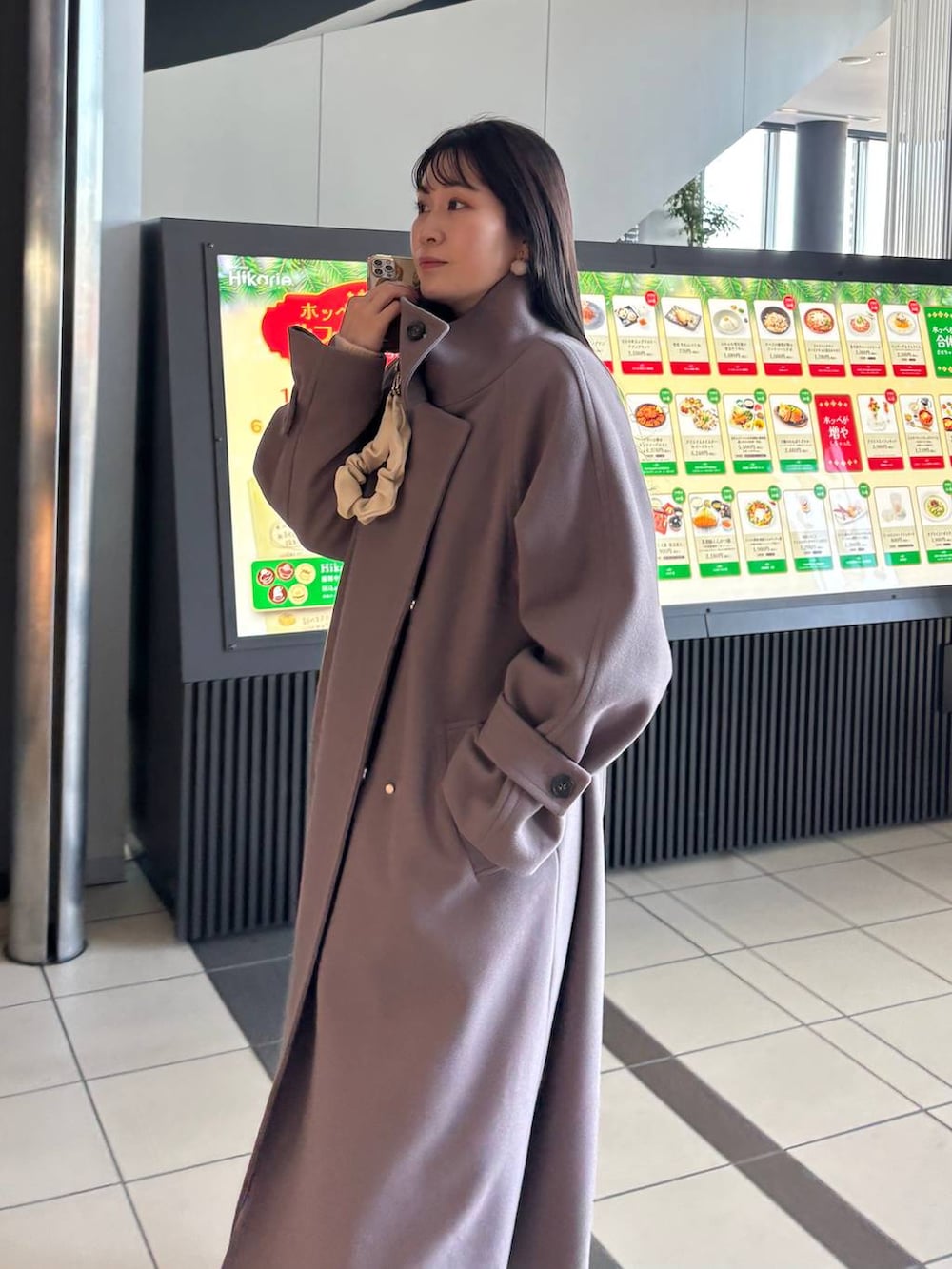 ブラウン系のチェスターコートを着用したレディースの冬コーディネートの2枚目の写真