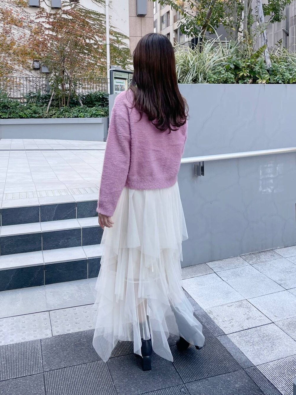 ピンク系のニット/セーター、グレー系のブーツ、ホワイト系のスカートを着用したレディースの冬コーディネートの2枚目の写真